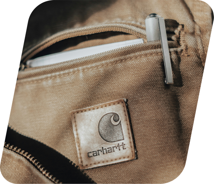 A Carhartt canvas bag's leather logo patch and zip pocket, a recognisable brand donation worth checking for online demand before it goes on the rail.